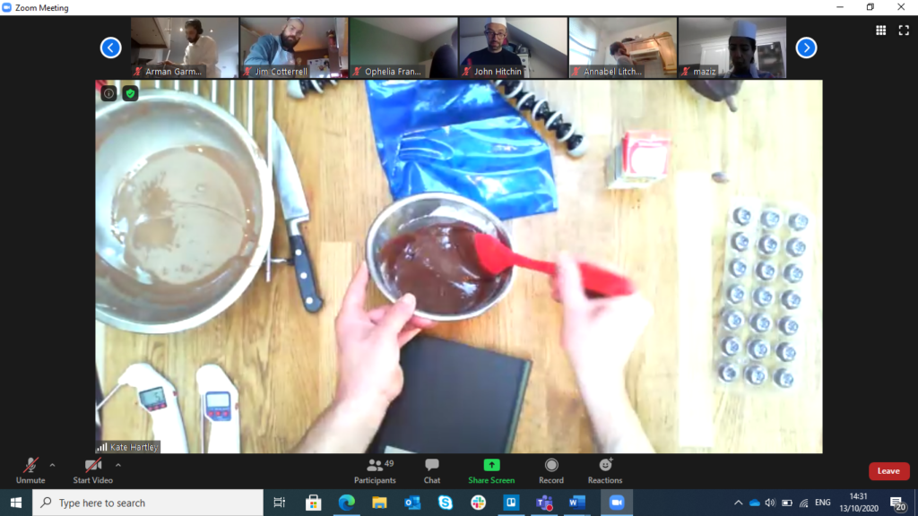 white hands holding a red spoon,  stirring melted chocolate in a bowl