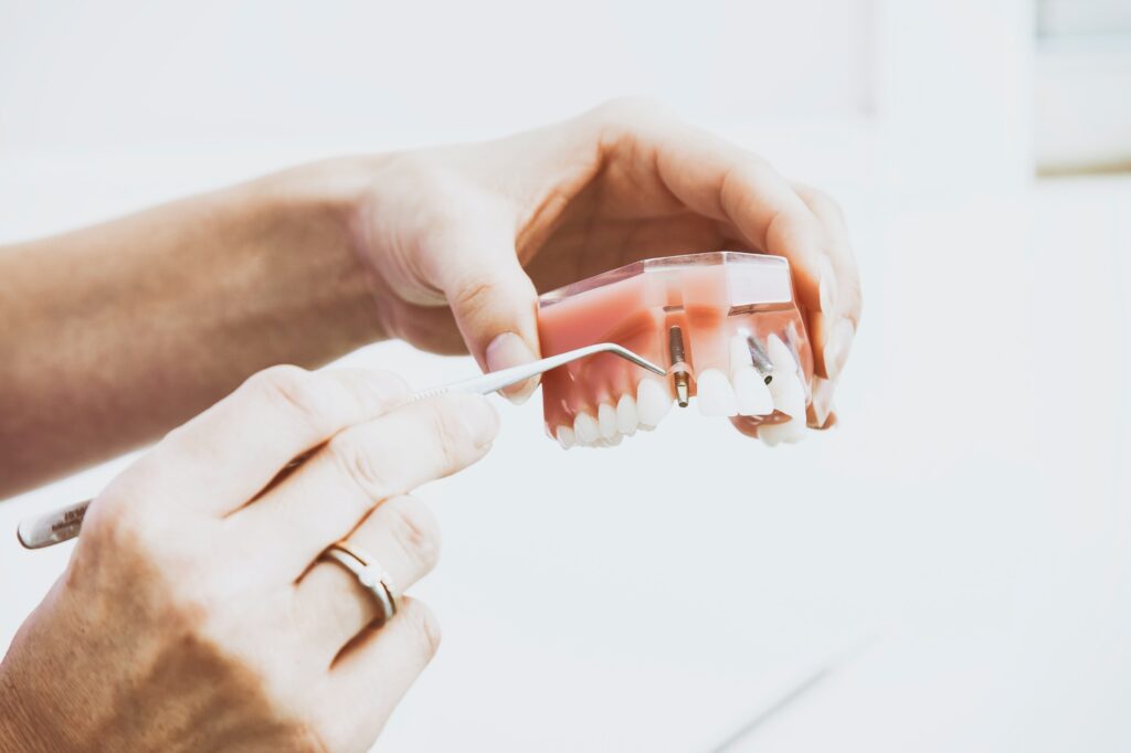 A dental technicians hands holding a set of dentures and a dental tool.