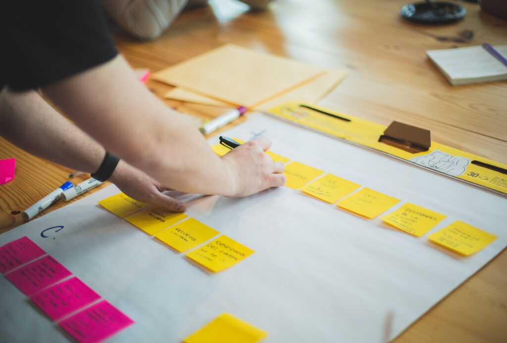 person writing on post it notes on a large sheet of white paper